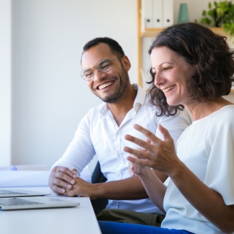 a man and woman smiling and working at a computer